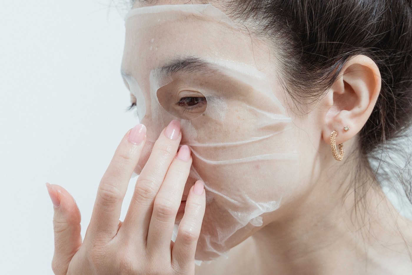 فردی در حال استفاده از ماسک ورقه‌ای روی صورت در محیطی روشن